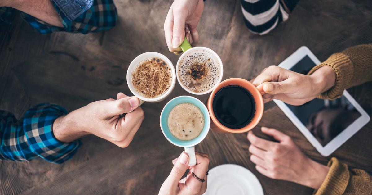 Overhead view photo of hands clinking coffee mugs