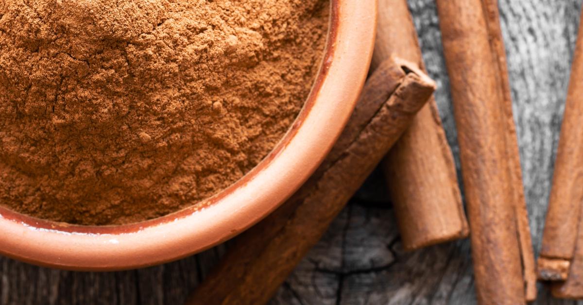 Bowl of powdered cinnamon and cinnamon sticks.
