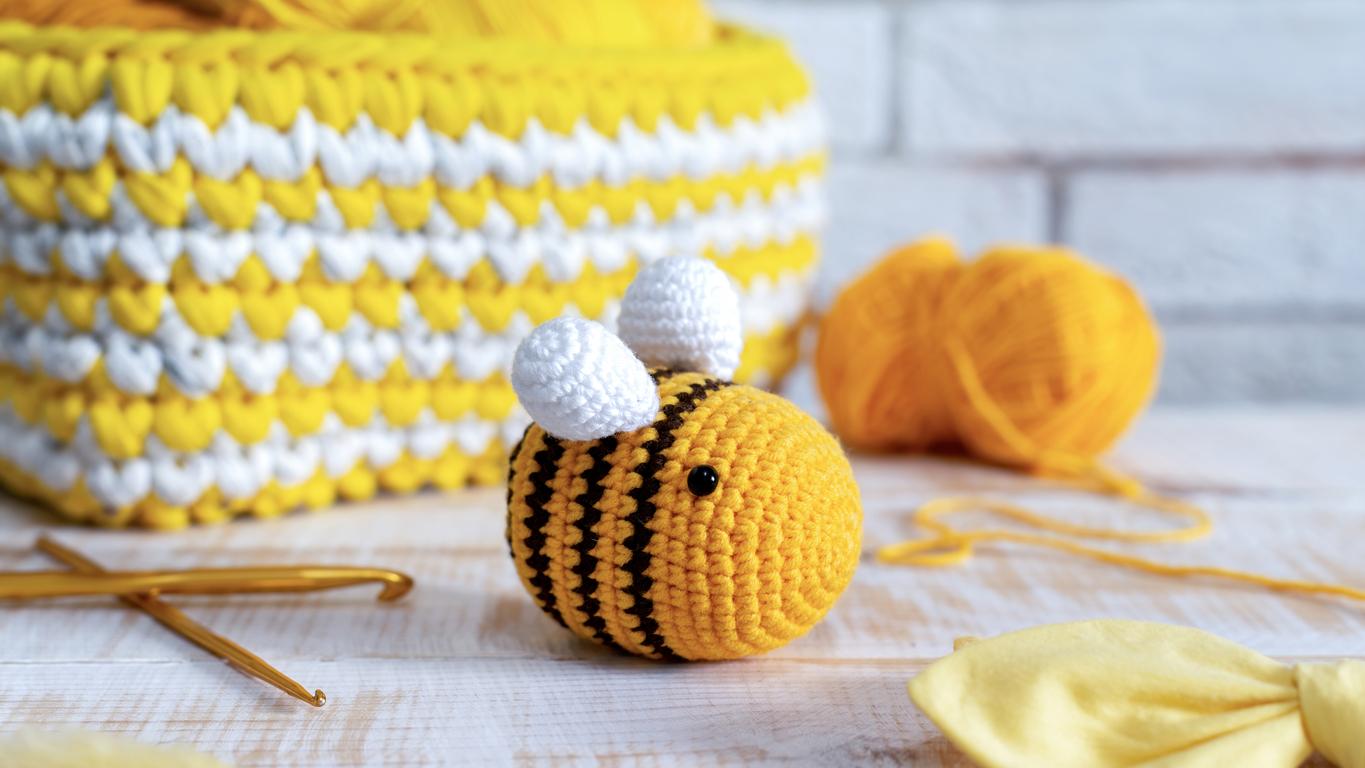 A bright yellow crochet bee on a white table.
