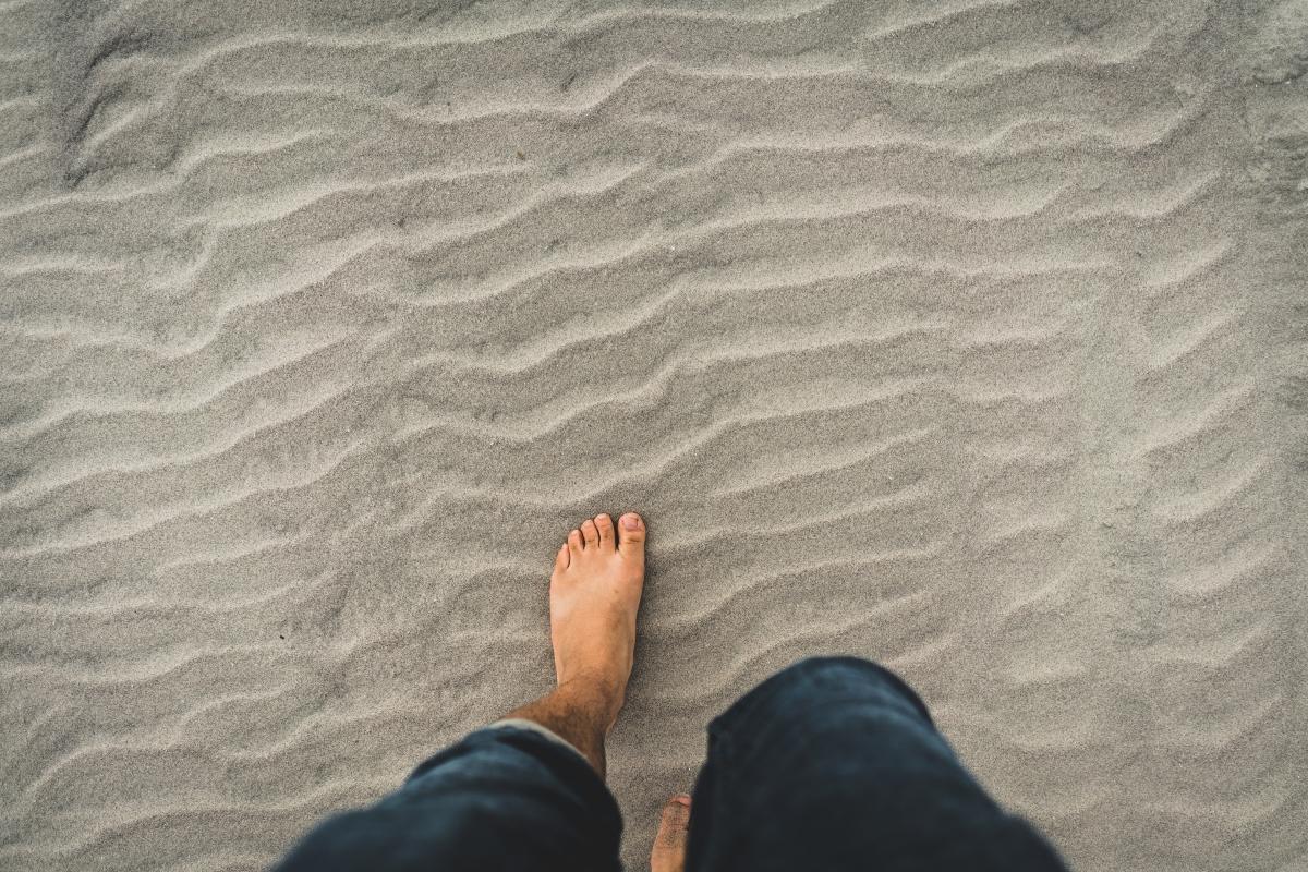 man stepping barefoot in sand