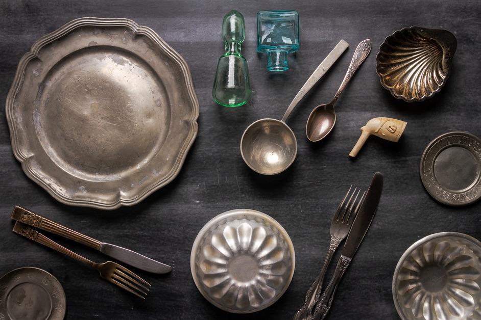 An overhead view of old metal dishware on a wooden table. 