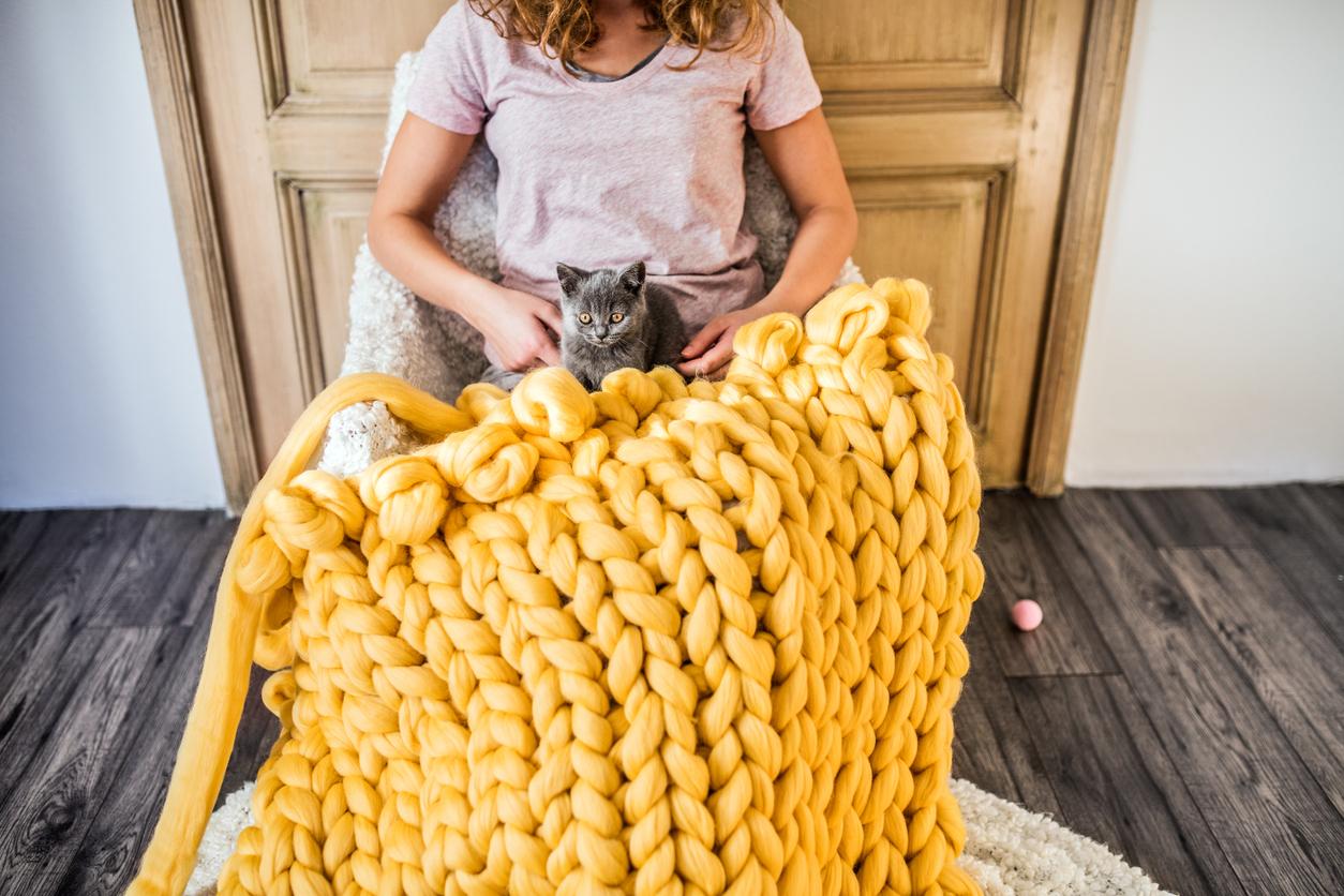 A yellow chunky knit blanket on someone's lap.