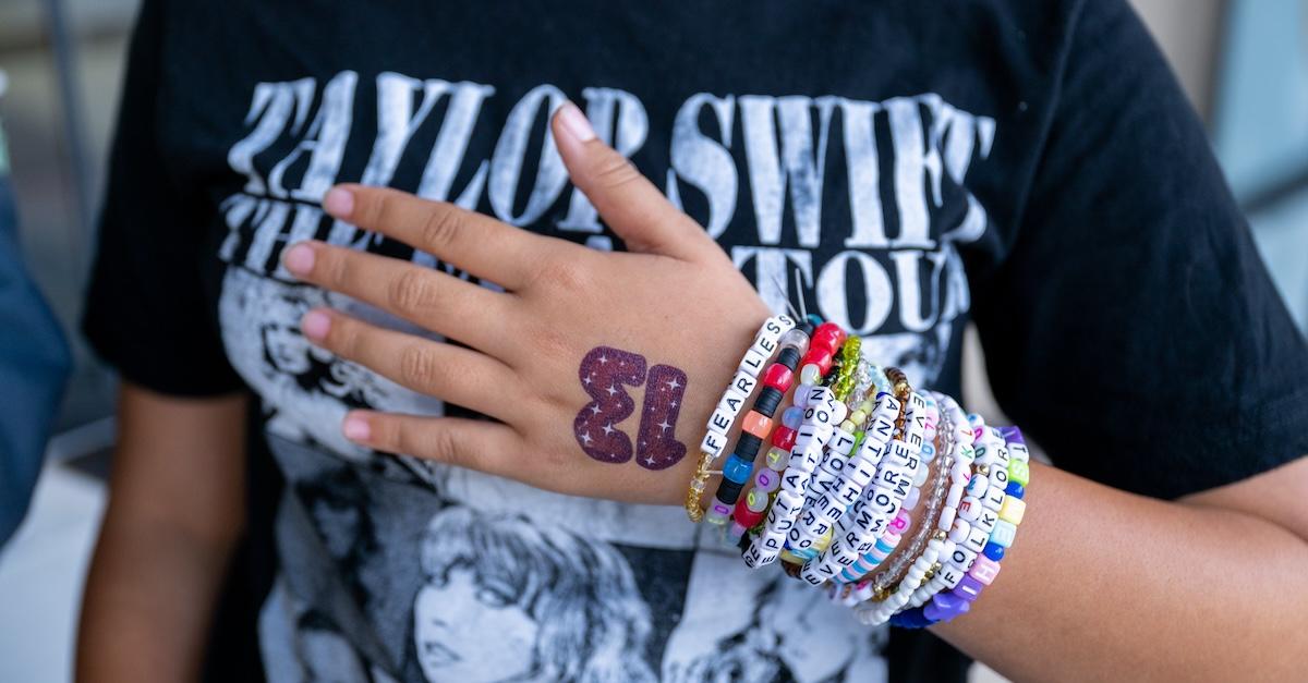 A closeup of a Taylor Swift fan with a Taylor Swift T-shirt and arms full of friendship bracelets attends the opening night theatrical release of 'Taylor Swift: The Eras Tour' at AMC Marina Marketplace 6 on Oct. 13, 2023 in Marina del Rey, Calif.