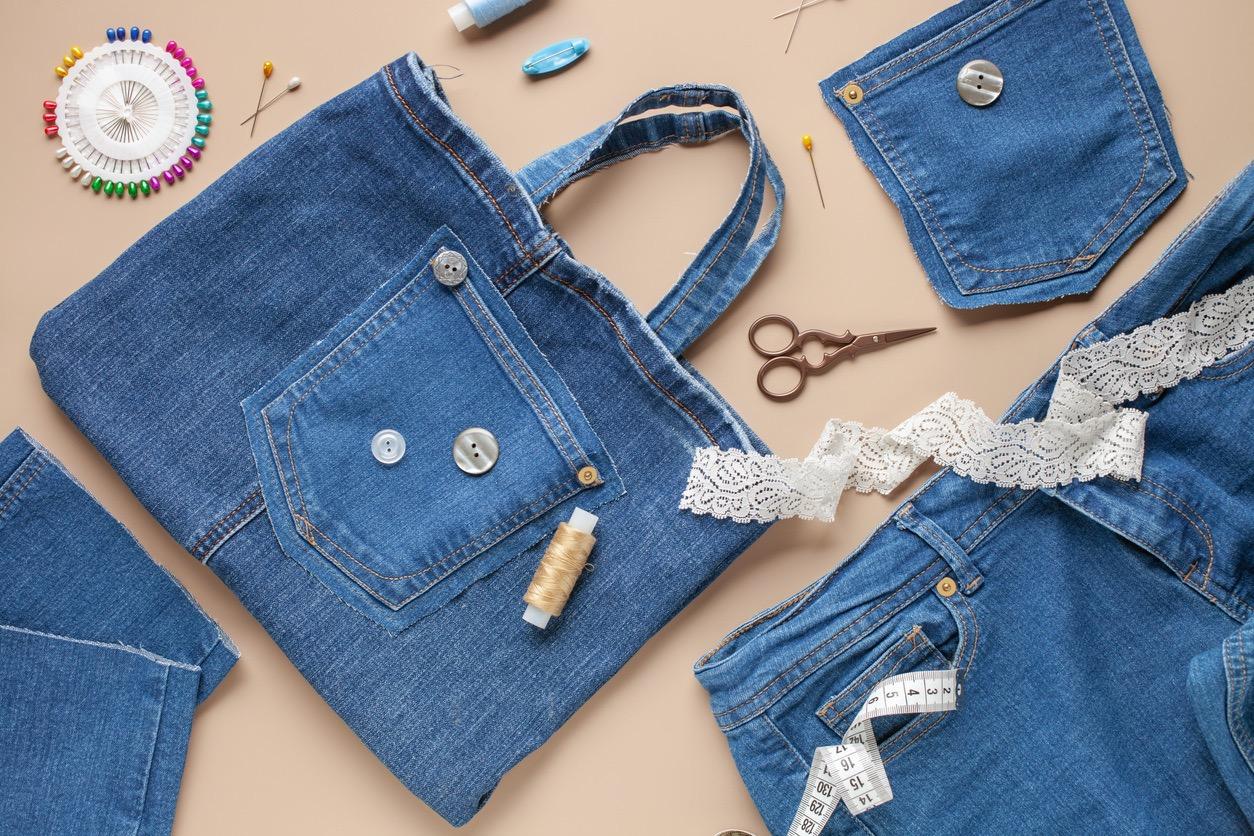 An upcycled, denim tote bag surrounded by other fabric and craft supplies.