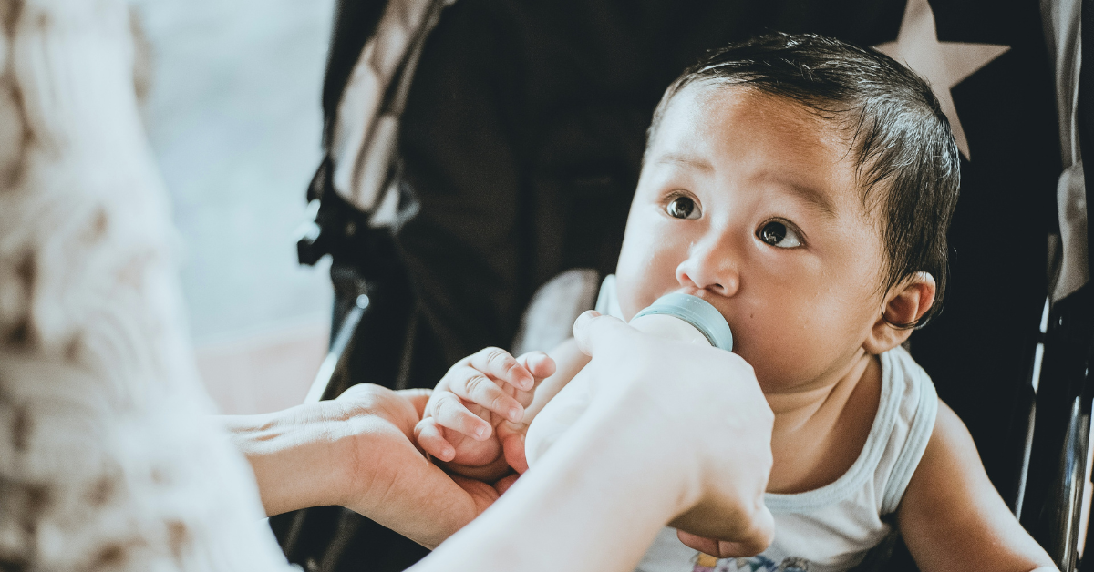 A woman feeds a baby formula using a baby bottle