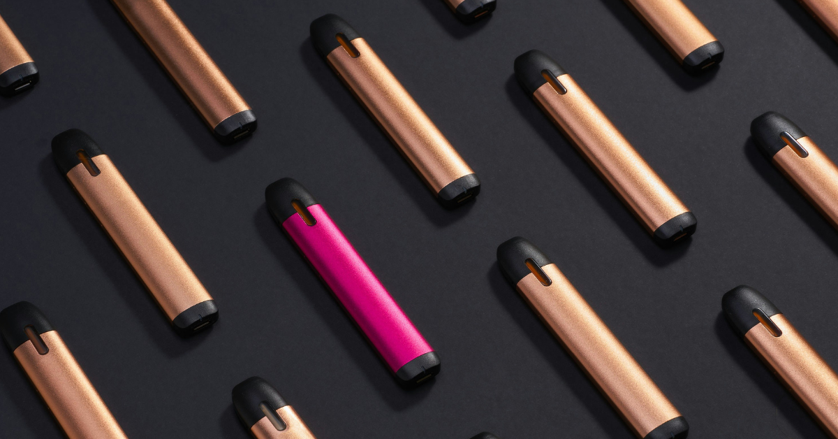 Pink and gold vapes sit against a black backdrop 