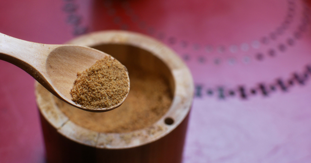 A brown wooden spoon holds ground cinnamon 