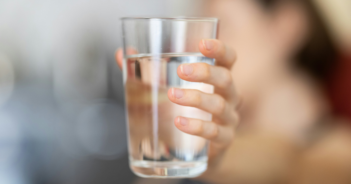 A hand holds a glass of water