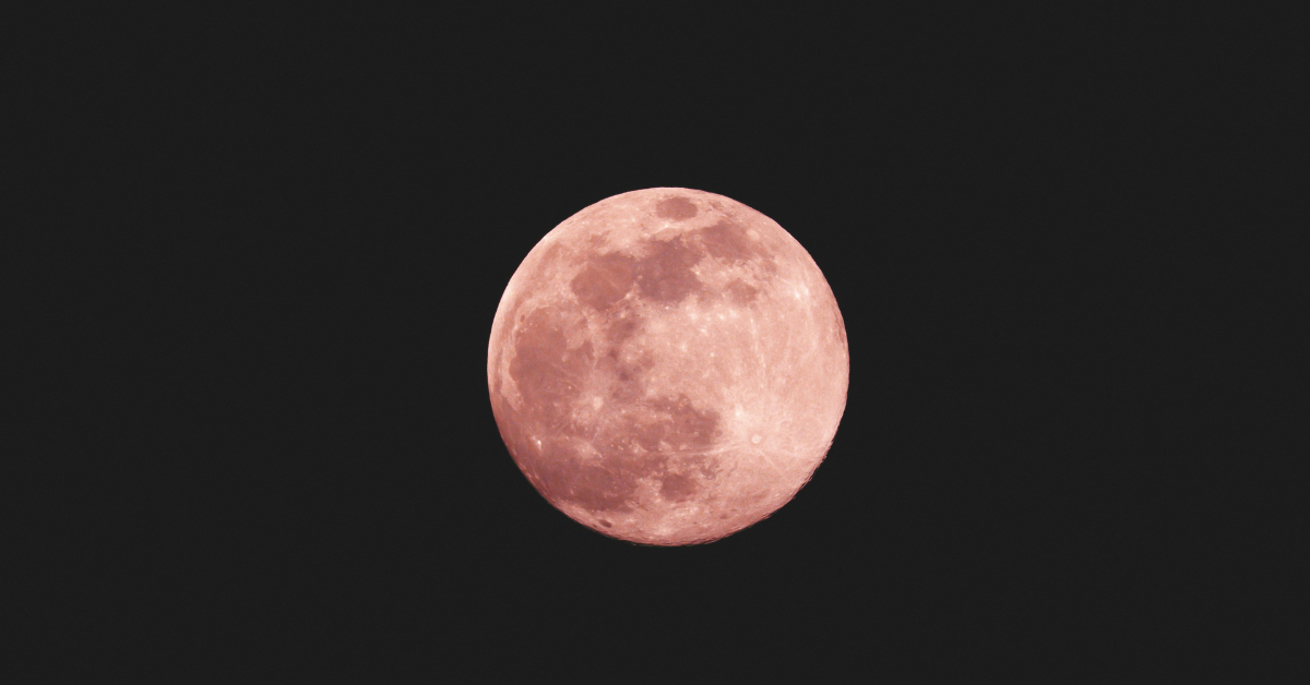 The moon appears pink while hanging in the night sky