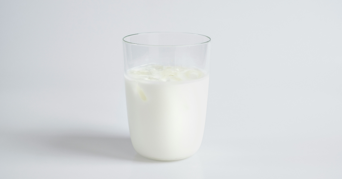 A glass of milk sits on a plain background 